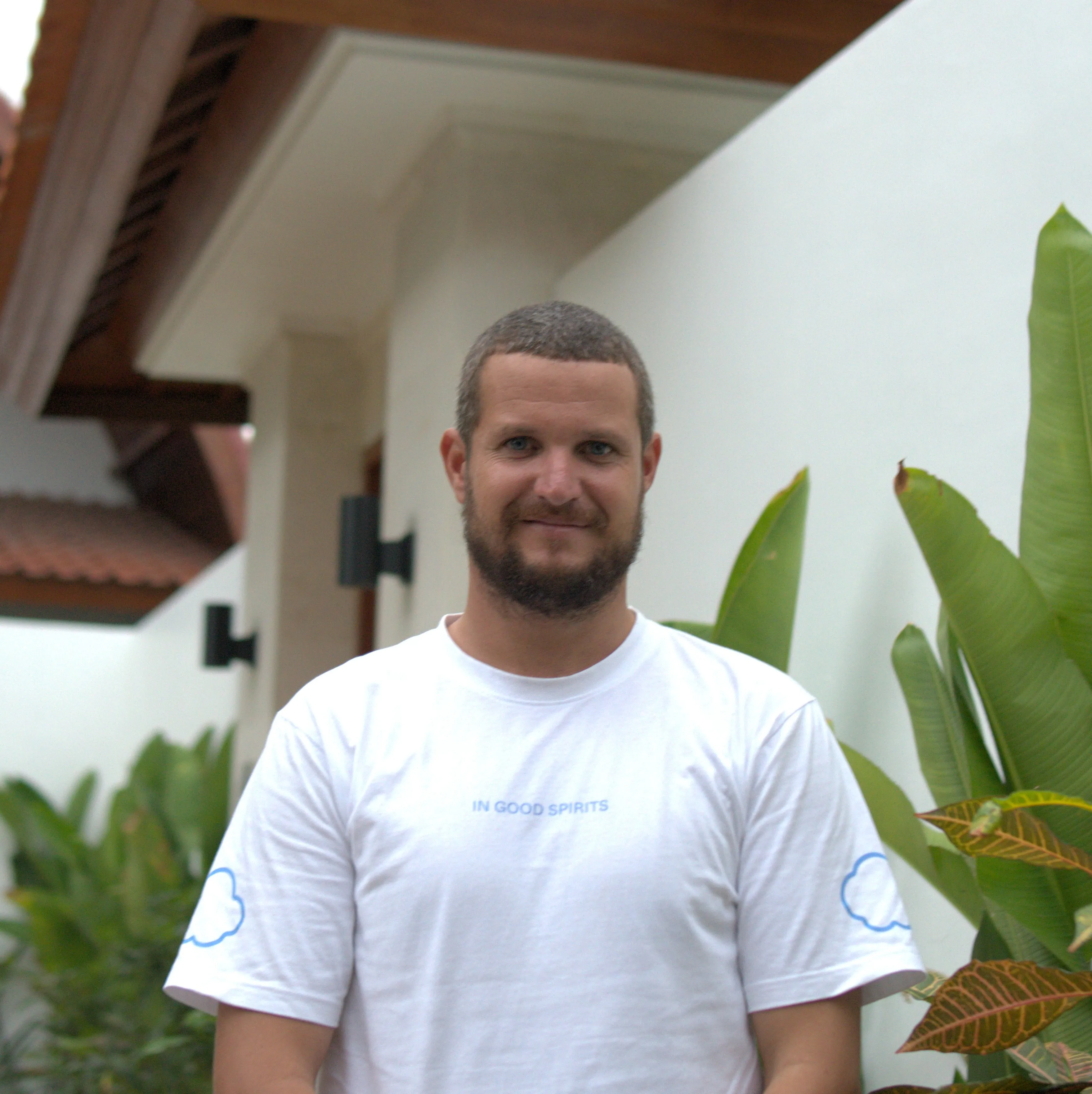 Santiago wearing a blue shirt sitting with confidence on a teak-wood bench outside a Villa in Bingin